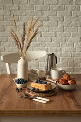 Still life in scandinavian style on a wooden kitchen table. Coffee, homemade cakes and fresh blueberries for breakfast. Concept for good morning wishes. Kinfolk style life. Copy space. Vertical photo
