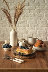 Still life in scandinavian style on a wooden kitchen table. Coffee, homemade cakes and fresh blueberries for breakfast. Concept for good morning wishes. Kinfolk style life. Copy space. Vertical photo
