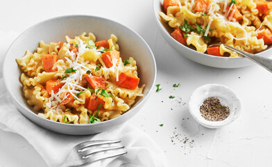 Italian pasta Mafalda Corta trafilata al bronzo with sauteed sweet potato, fennel, parmesan grated cheese on white background. Vegetarian meatless food.