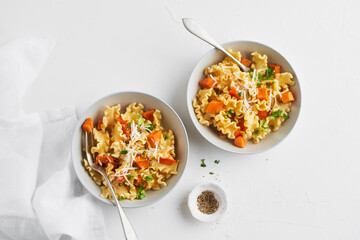 Italian pasta Mafalda Corta trafilata al bronzo with sauteed sweet potato, fennel, parmesan grated cheese on white background. Vegetarian meatless food. Copy space, no people. Top view.