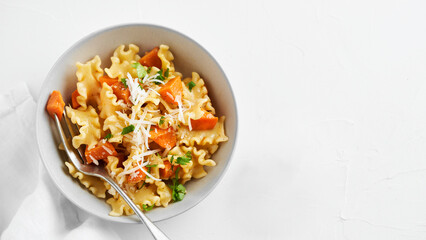 Italian pasta Mafalda Corta trafilata al bronzo with sauteed sweet potato, fennel, parmesan grated cheese on white background. Vegetarian meatless food. Copy space, no people. Top view.