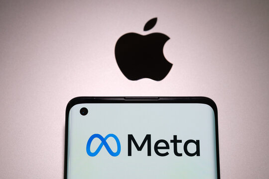 Meta company logo seen on smartphone which is plased on top of macbook with blurred apple logo. Concept. Stafford, United Kingdom, July 31, 2022