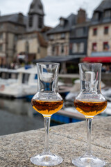 Tasting of apple calvados drink in old Honfleur harbour with boats and old houses on background, Normandy, France