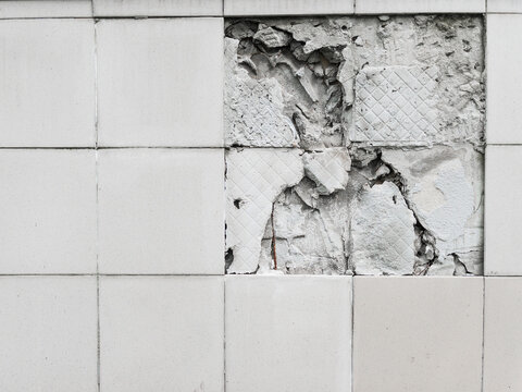 A wall with a broken off gray tile from the wall