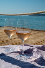 Glasses of cold rose wine from Provence served outdoor on wooden yacht pier with view on blue water and white sandy beach Plage de Pampelonne near Saint-Tropez, France