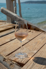 Glasses of cold rose wine from Provence served outdoor on wooden yacht pier with view on blue water...