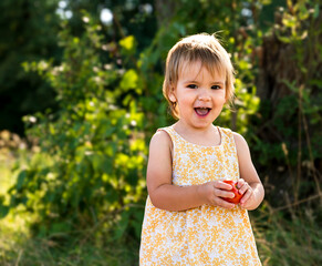 Cheerful girl holding a tomato in her hands and laughing