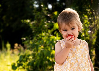 little girl biting a tomato