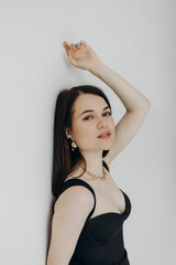 Fototapeta premium A girl in a black dress stands on a white background