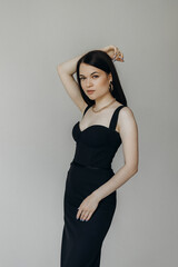 A girl in a black dress stands on a white background