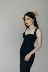 A girl in a black dress stands on a white background