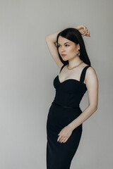 Fototapeta premium A girl in a black dress stands on a white background