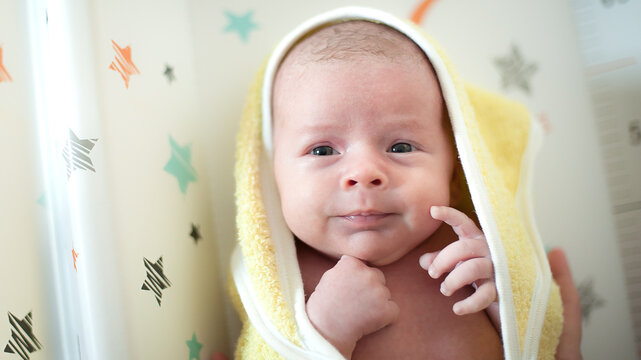 Close-up detail portrait of cute little peaceful newborn baby chield lies wrapped in a towel after a bath. Love and family emotion