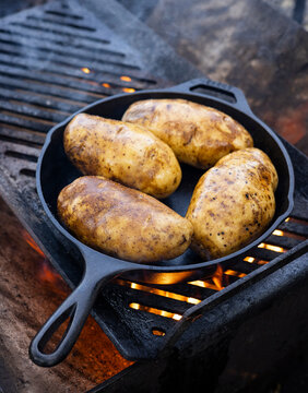 Outdoor camp cooking on cast iron pans with an open  wood burning flame