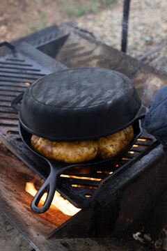 Outdoor camp cooking on cast iron pans with an open  wood burning flame