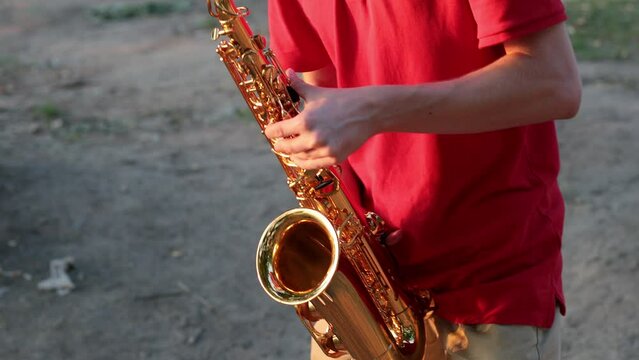 Hands and saxophone close up. The guy plays a wind instrument.