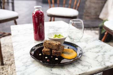 vegetable croquettes on a plate, juice, glass and sauce on the table