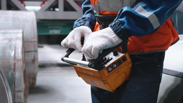 Close-up. Remote control crane beam in an industrial warehouse. The worker is loading and unloading.