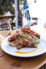 plate with potatoes and hot dogs with different sauces, glass and bottle of water on the table