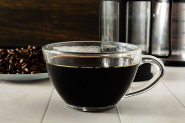 black coffee on transparent glass cup, with beans