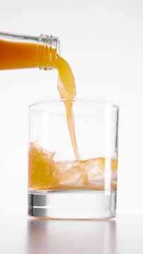 Vertical shot of orange juice being poured into the glass