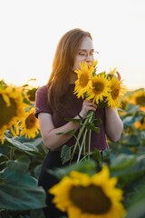 Beautiful young girl enjoying nature on the field of sunflowers at sunset