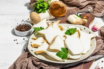 Fresh Pleurotus eryngii mushrooms on wooden background. Raw king oyster eringi with spices and herbs