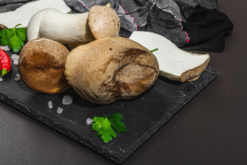 Fresh Pleurotus eryngii mushrooms on black stone concrete background. Spices and herbs
