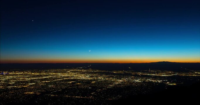 Aerial Lockdown Scenic View Of Gold Illuminated City While Moon And Stars Moving Downwards - Albuquerque, New Mexico