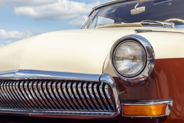 Headlight of an old car, close-up of a round headlight. Classic car show, close-up on vehicle headlights, vintage color