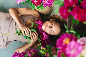 an attractive woman on the floor with a bouquet of peonies.