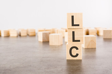 LLC text as a symbol on cube wooden blocks. many wooden blocks in the background.