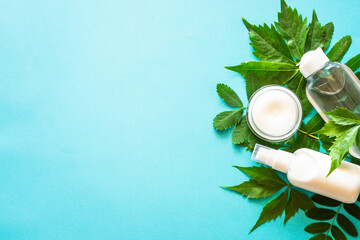 Natural cosmetics concept. Skin care product, cream, serum, soap, mask with green leaves. Flat lay image on blue with space for your text.