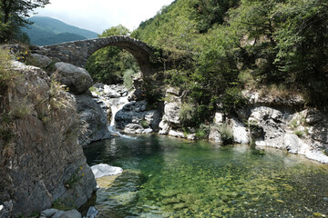 Fototapeta na wymiar ancient stone bridge over beautiful mountain river in liguria, italy