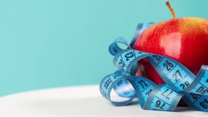 Apple and centimeter tape on a blue background rotating, weight loss and healthy eating