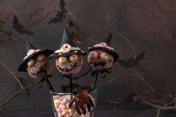 Homemade Halloween cakes pops as monsters with dark chocolate, decorated witch hat from mastic....