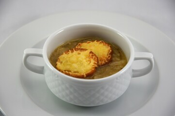 French onion soup with croutons covered  cheese in white bowl