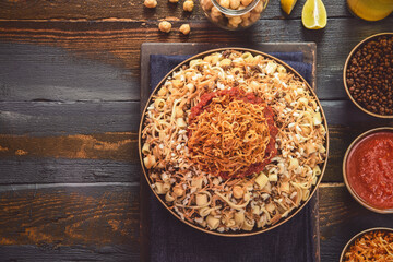 Arabic cuisine; Traditional Egyptian food: Delicious Kushary or Koushari of rice, pasta, chickpeas, lentils,crispy fried onions,fresh lemon and tomato garlic sauce on a plate.Top view with copy space.