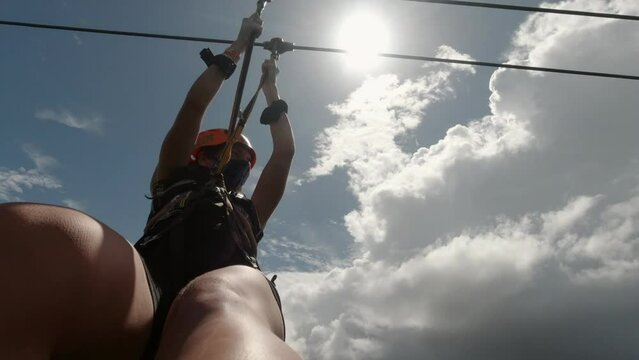 Female on a zip line against the blue sky in Riviera Maya, Mexico