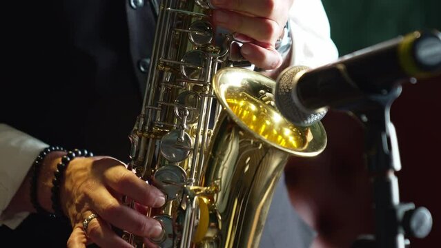a man plays the saxophone near the microphone on stage. 