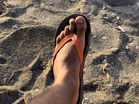Male leg resting on a sandy beach