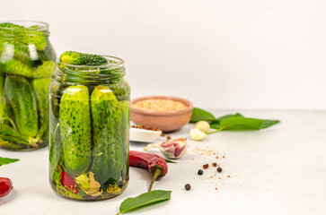 Raw cucumbers in glass jars for preservation on a white table with space for text