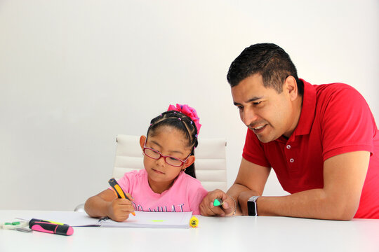 Latino dad and daughter, teacher and student draw in a notebook with colors in this back to school to improve skills with Autism Spectrum Disorder (ASD)
