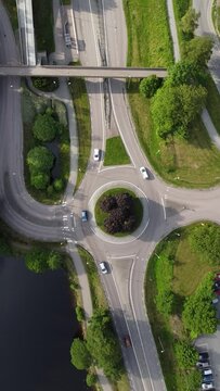 Vertical drone video of traffic roundabout with driving cars.