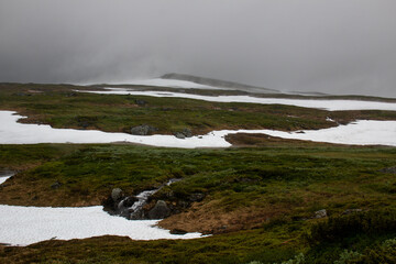 Fototapeta premium The patches of snow creating fog around the hiking trail between Storulvan and Blahammaren mountain stations, early July, Jamtland, Sweden