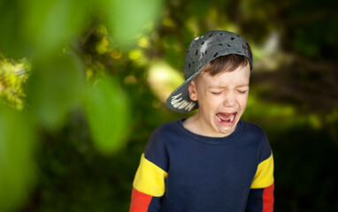 the boy is crying loudly in the shade of the trees © Ольга Потылицына
