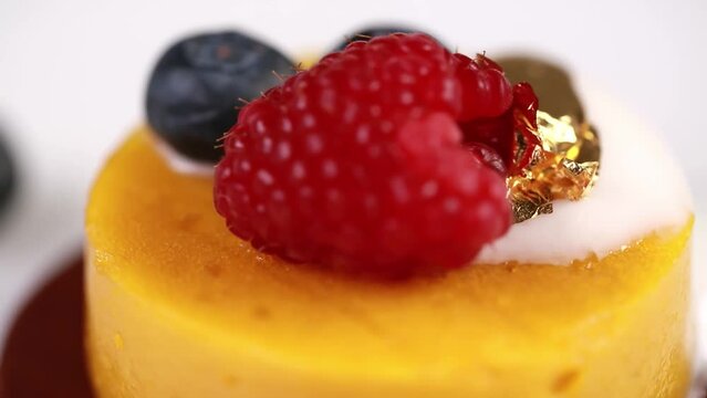 Closeup of fresh delicious mango mousse decorated with blueberries and a raspberry