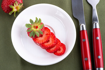 slices of strawberries on saucer and silvervare. Delicious and fresh dissert on the dinner table.