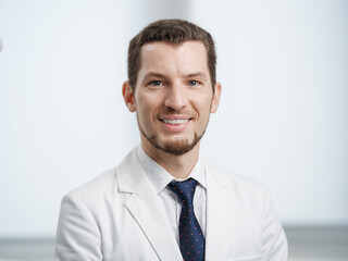 Closeup portrait of smiling male dentist in white lab coat looking at camera