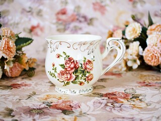 Antique cup of tea with saucer ,yellow orange rose flowers background ,porcelain vintage style ,old English coffee cup still life for wallpaper ,romance roses backgrounds 